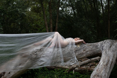 Midsection of woman by tree trunk in forest