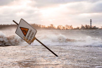 Huge waves crashing down the coast of latvia braking signs.