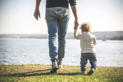 Rear view of mother and son in water