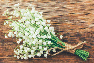 White scented lilies of the valley on an old wooden plank closeup