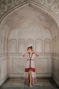 Full length of woman standing against wall in building