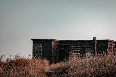 Abandoned building on field against clear sky