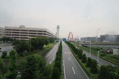 Vehicles on road against sky in city