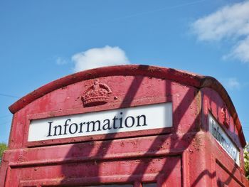 Low angle view of old telephone booth against sky