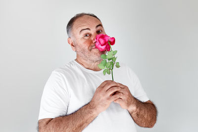 Portrait of man holding rose against white background
