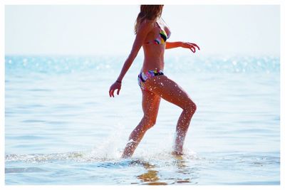 Midsection of woman splashing water in sea