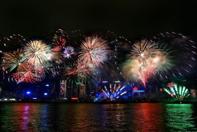 Scenic view of firework display over river and city at night