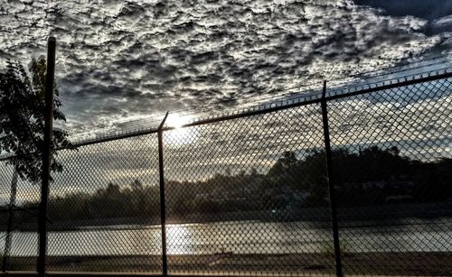 Chainlink fence against sky during sunset