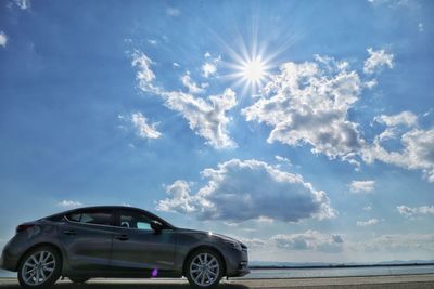 Car on sea against sky on sunny day