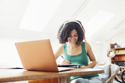 Portrait of young woman using laptop at home