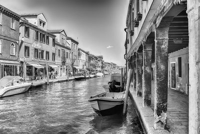 Boats moored in canal amidst buildings in city