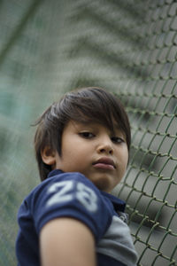 Close-up of boy against chainlink fence