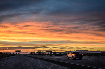 Cars on road against orange sky