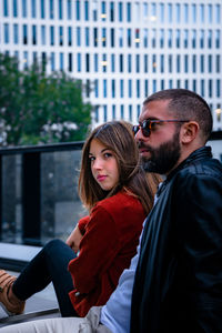 Portrait of young woman with friend sitting in city