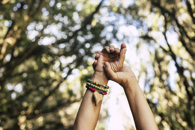 Low angle view of person hand holding against trees