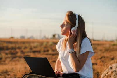 Young woman using mobile phone while sitting on land