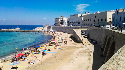 Panoramic view of people on beach against blue sky