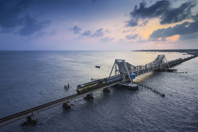 High angle view of railway bridge over sea against sky during sunset