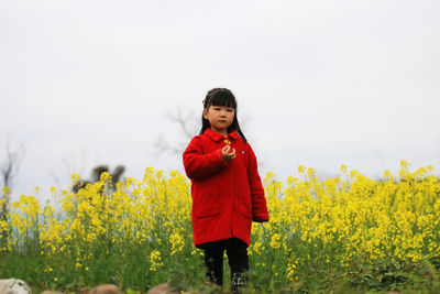 Cute girl standing on field against sky