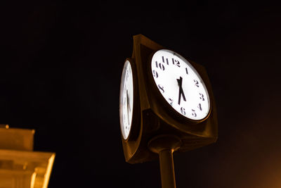 Low angle view of illuminated clock at night