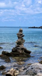 Stack of rocks in sea against sky