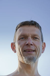 Low angle portrait of wet mature man against sky