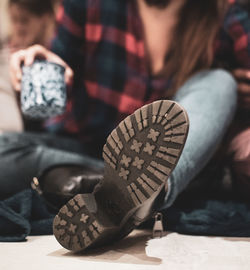 Low section of woman holding coffee cup while sitting on floor