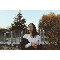 Portrait of young woman against railing