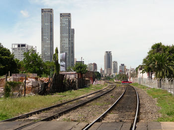 Railroad tracks in city against sky