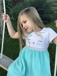 Smiling blond girl sitting on swing