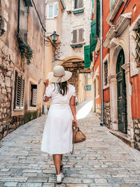 Woman walking on cobblestone street amidst buildings in city