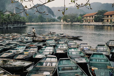Boats moored at harbor by lake against buildings