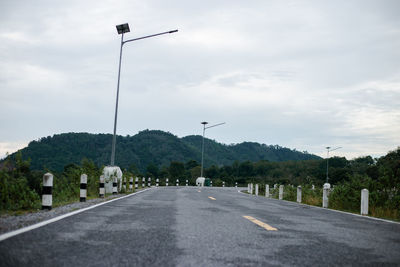 Street lights by road against sky