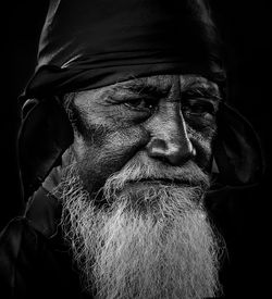 Close-up portrait of bearded mature bearded man against black background