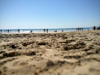 Surface level of sand at beach against clear blue sky