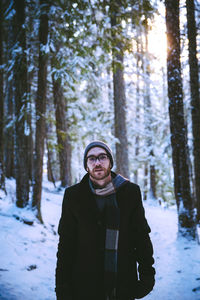 Portrait of man standing in forest during winter