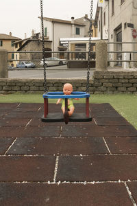 Boy playing on swing in playground