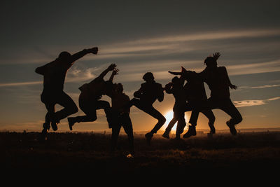 Silhouette people on field against sky during sunset