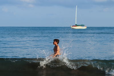 Boy looking away while standing in sea