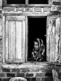 Portrait of man sitting by window against building