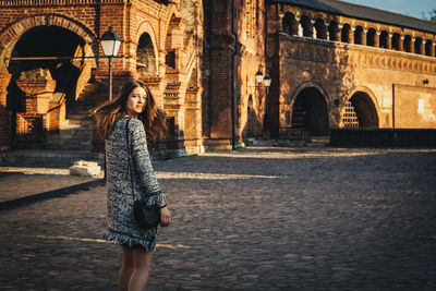 Portrait of woman walking against old ruin