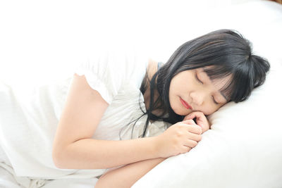 Portrait of young woman lying on bed at home