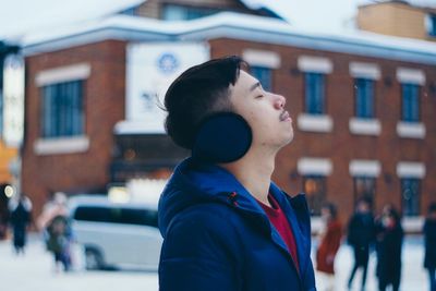 Portrait of young man standing in city during winter