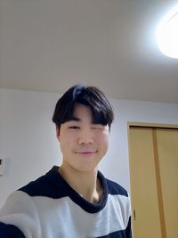 Portrait of smiling boy against wall at home