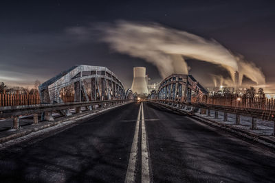 View of bridge and factory against sky