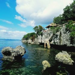 Scenic view of rocks by sea against sky