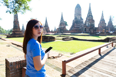 Young woman wearing sunglasses standing at temple