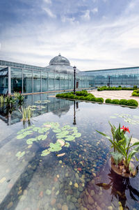 Modern building by pond against sky