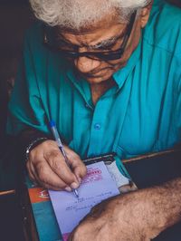 Midsection of man holding paper in pen