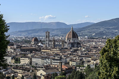 Aerial view of city by mountains against sky